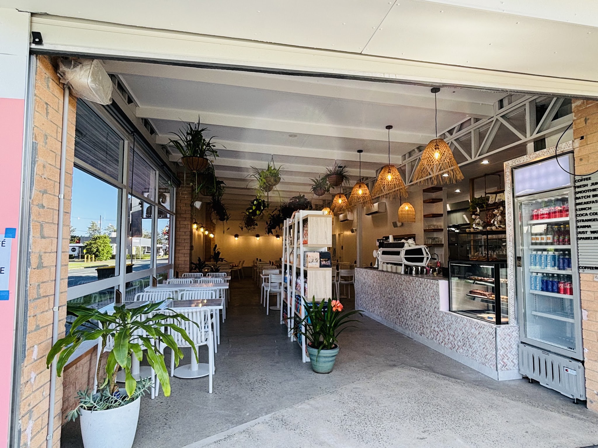 The open front of Small Wonder Cafe on Beerburrum Rd, with hanging plants, rattan lights and the coffee counter